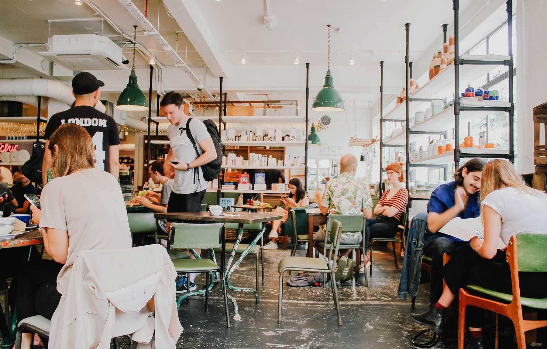 Busy coffee shop interior with customers seated at tables and walking around.