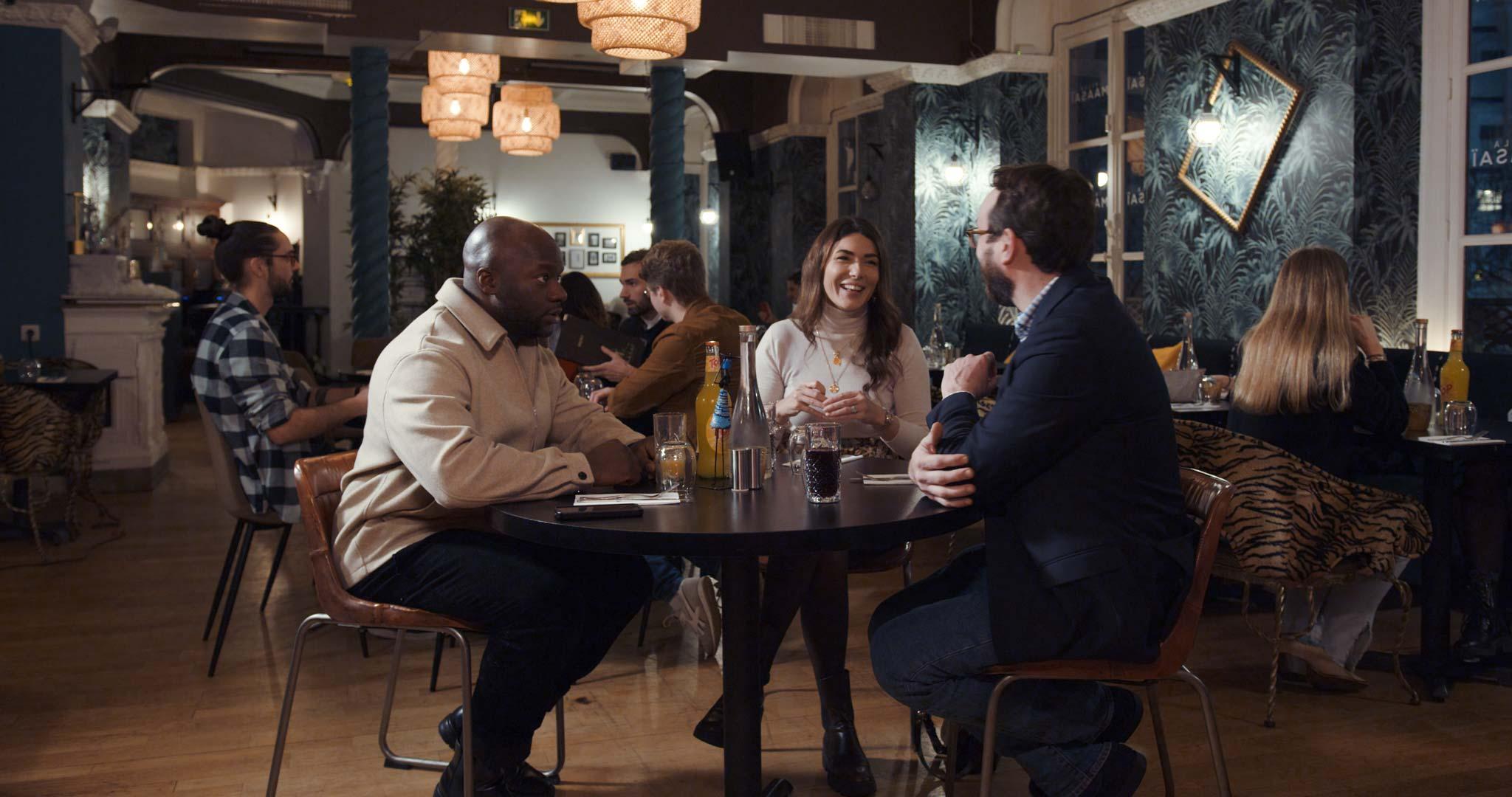 Groupe de personnes en train de discuter à une table de restaurant.