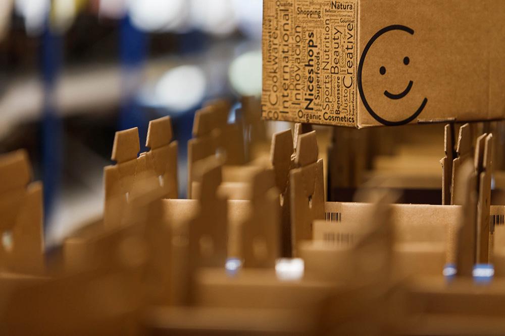 Kartonbox mit einem Lächeln auf der Seite zwischen anderen Paketen.