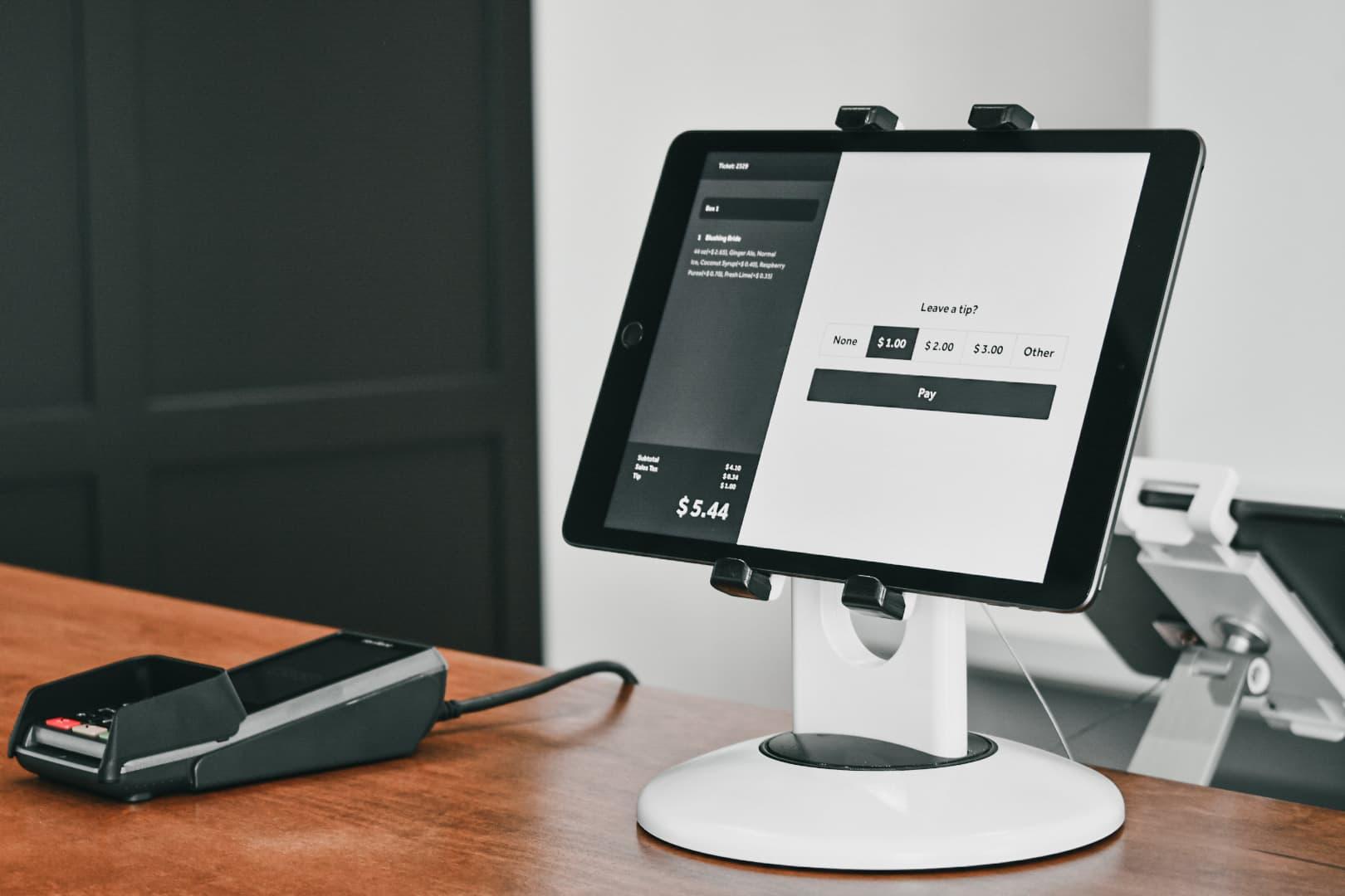 Tablette avec écran de paiement Adyen proposant des options de pourboire et un terminal de paiement par carte.