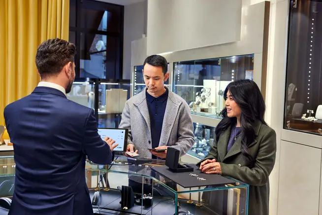 A couple at a jewelry store counter paying for earrings by tapping their card on Adyen's P400 terminal.
