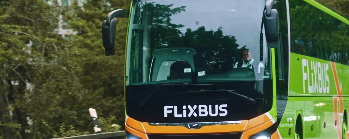 Green and orange Flixbus with driver at the wheel.