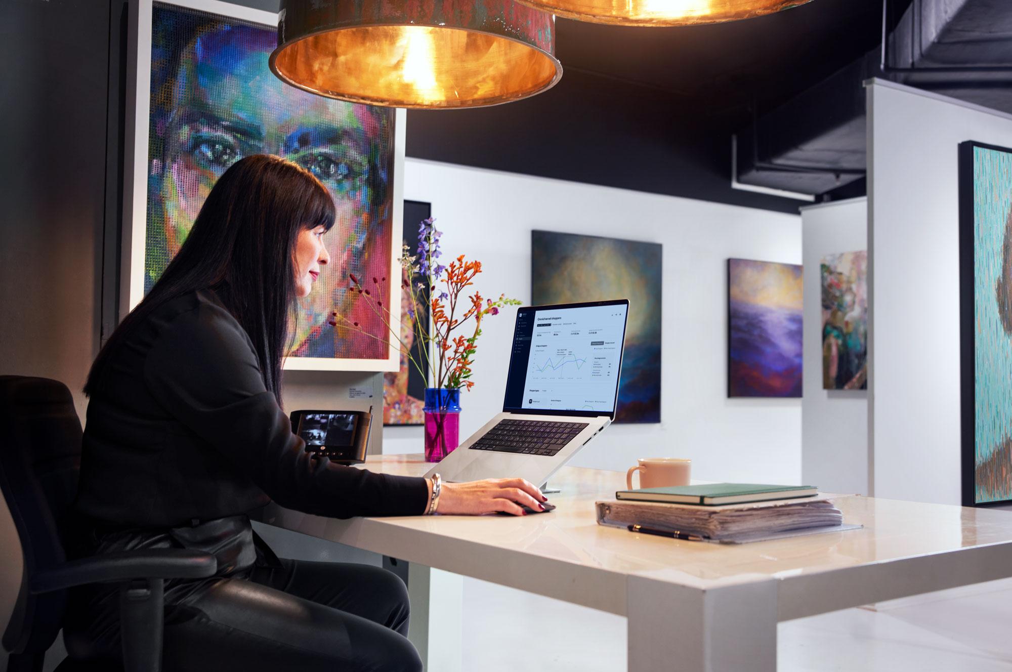 Art gallery employee looking at a payment dashboard on their laptop.