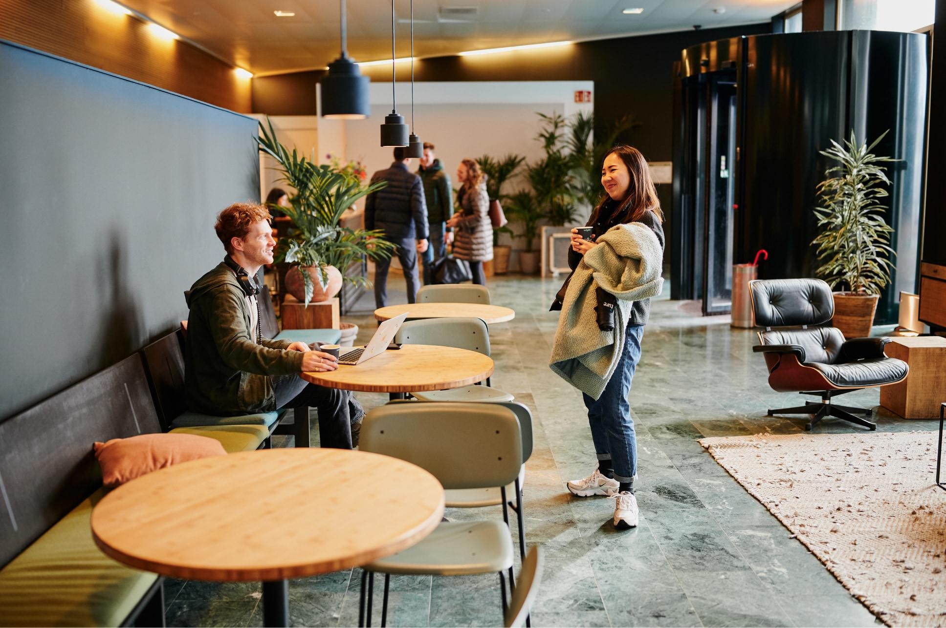 A modern office lounge area with individuals working and socializing.