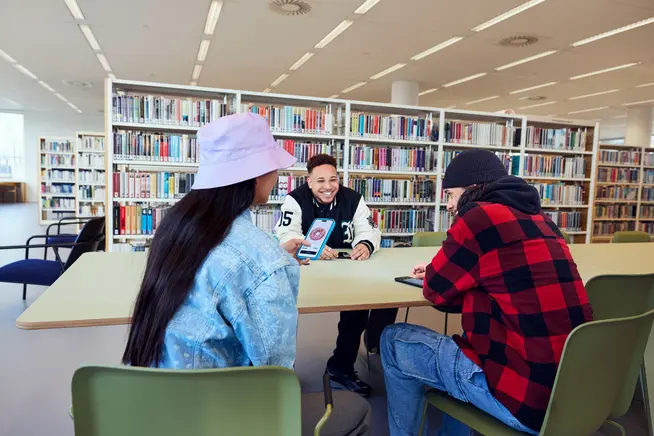 Un grupo de jóvenes en una biblioteca pidiendo donas en una aplicación móvil.