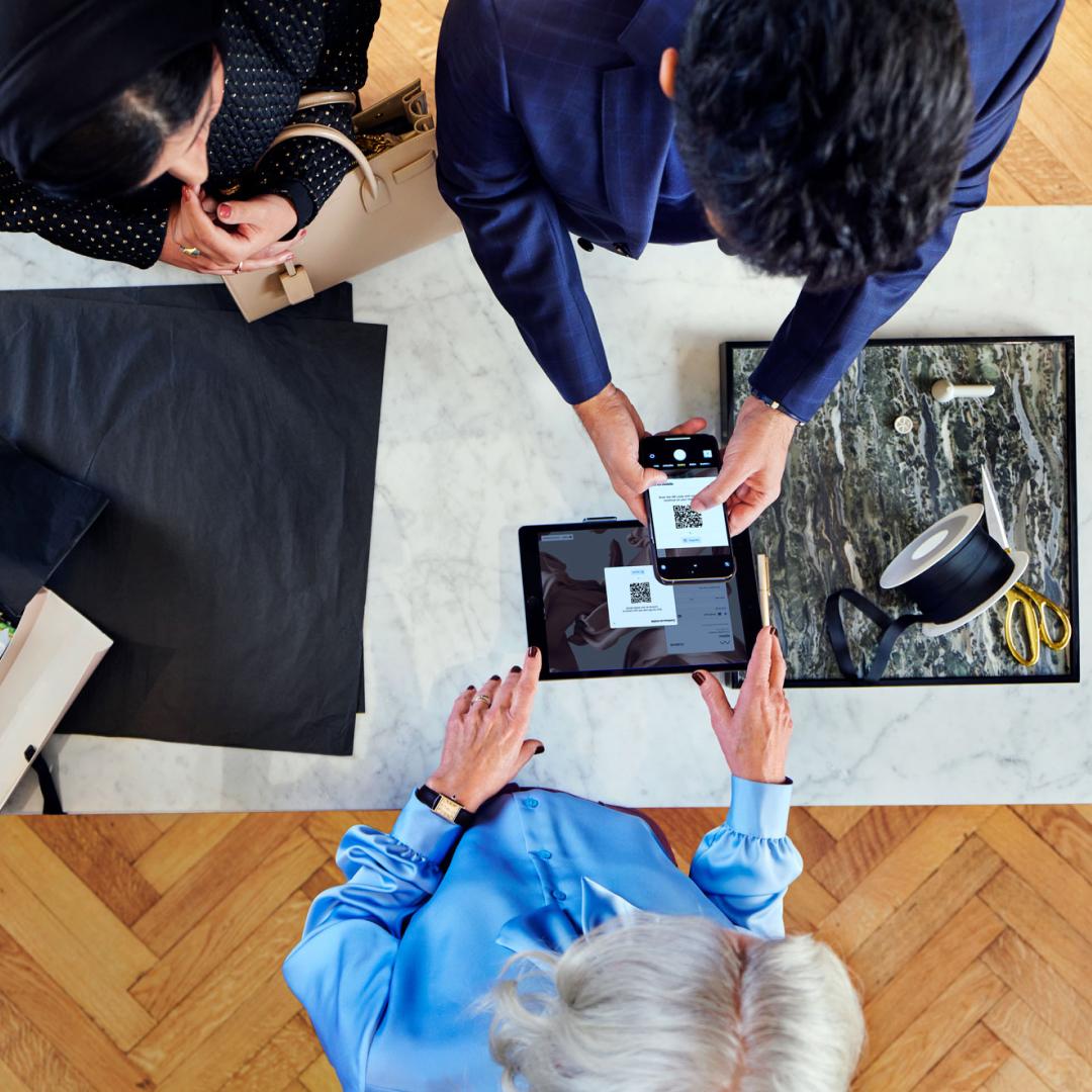 Two people using a smartphone and tablet for digital payment transaction with Adyen's platform.