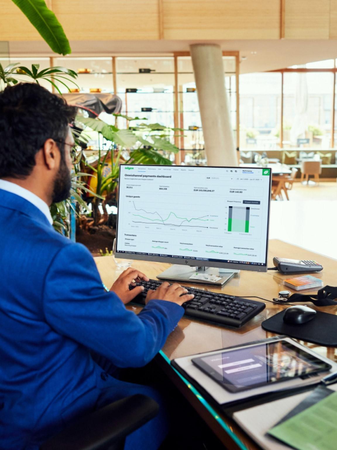 A professional working on a computer with Adyen omnichannel payments dashboard on the screen.