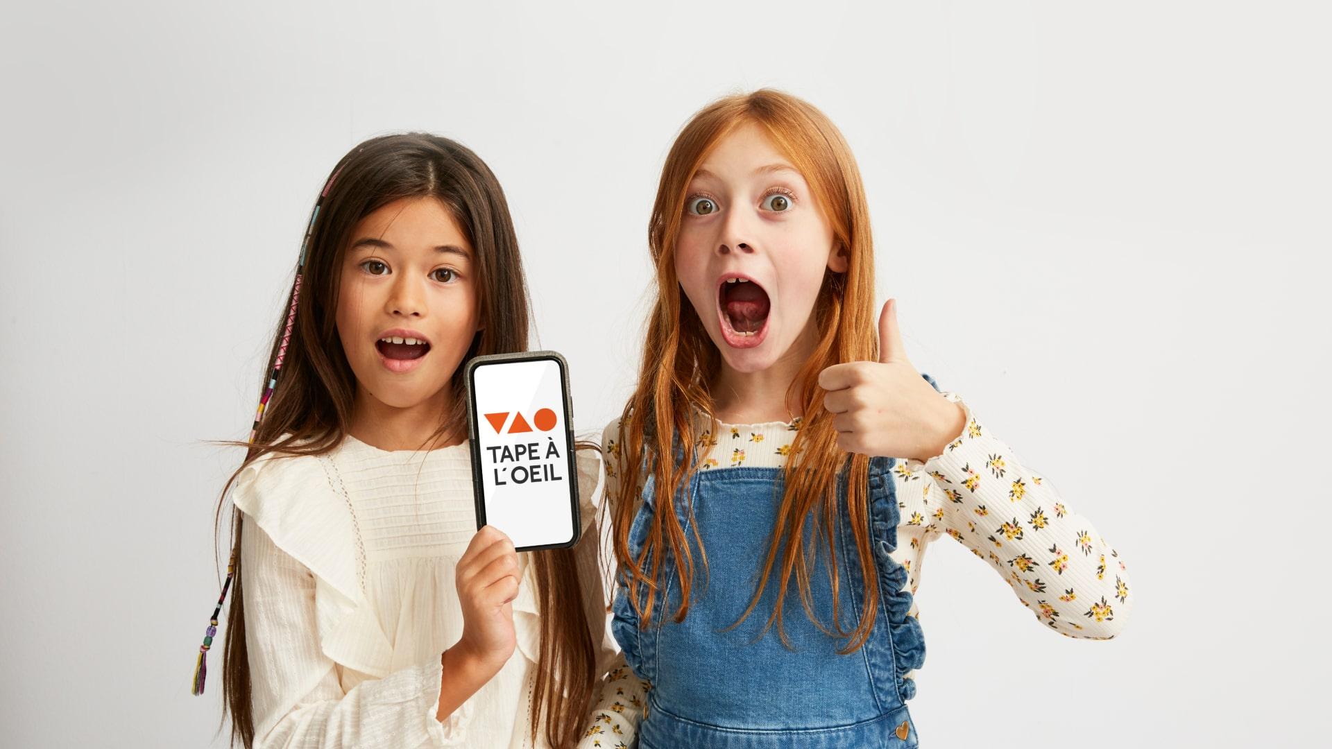 Deux enfants excités, l'un tenant un smartphone avec le logo Adyen sur l'écran.