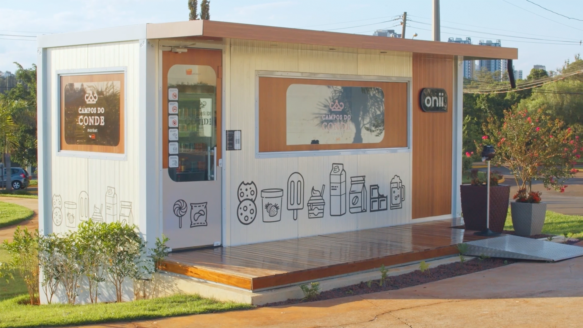 Pequeno quiosque moderno de lanches com várias ilustrações de comida e logotipos de empresas na parte externa