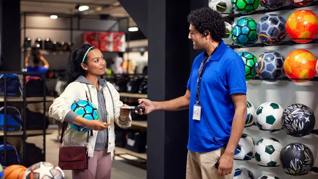 Women buying football in a retail store