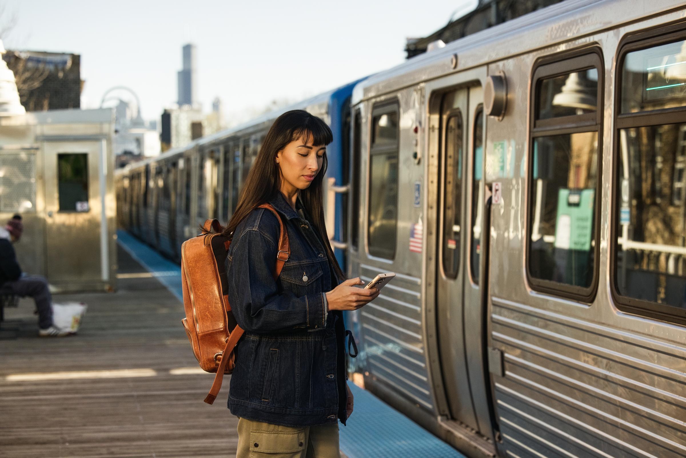 A traveler using a mobile device near an Adyen-enabled train station platform.