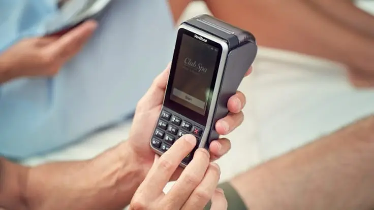 Close-up of a person's hands using an Adyen payment terminal.
