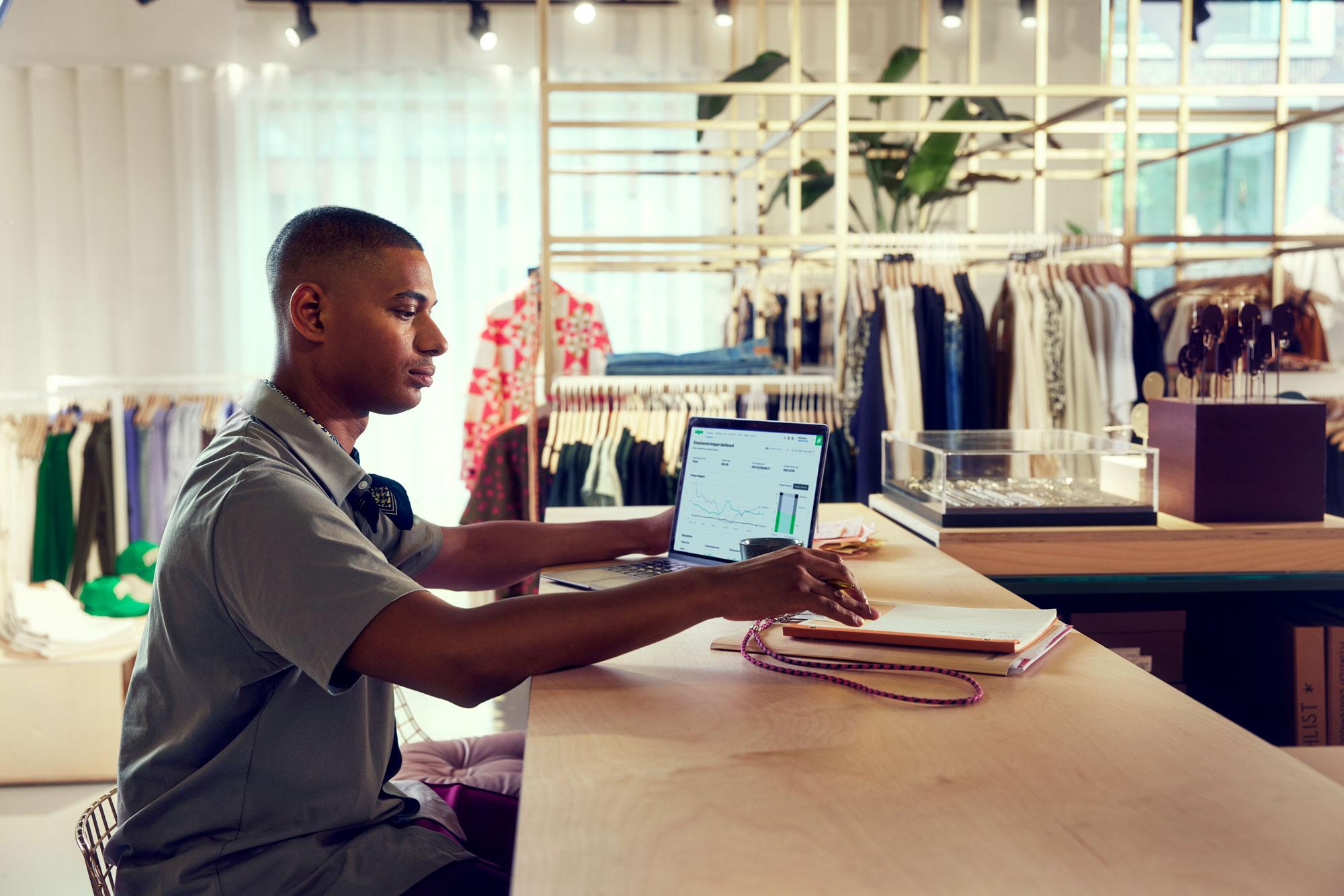 Um funcionário de uma loja de moda olhando o painel de pagamentos no seu laptop.