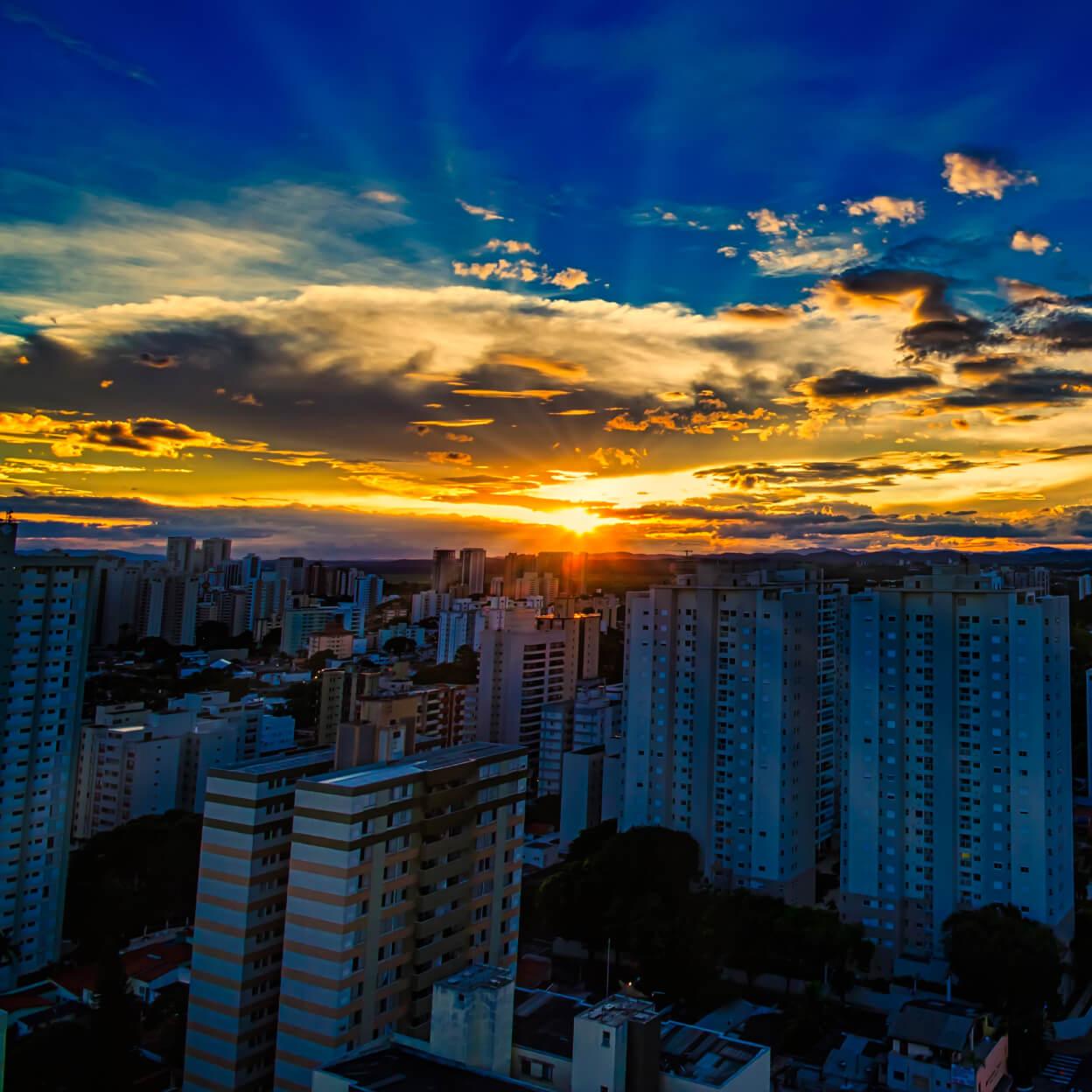 Puesta de sol con colores vibrantes sobre un paisaje urbano con edificios altos.