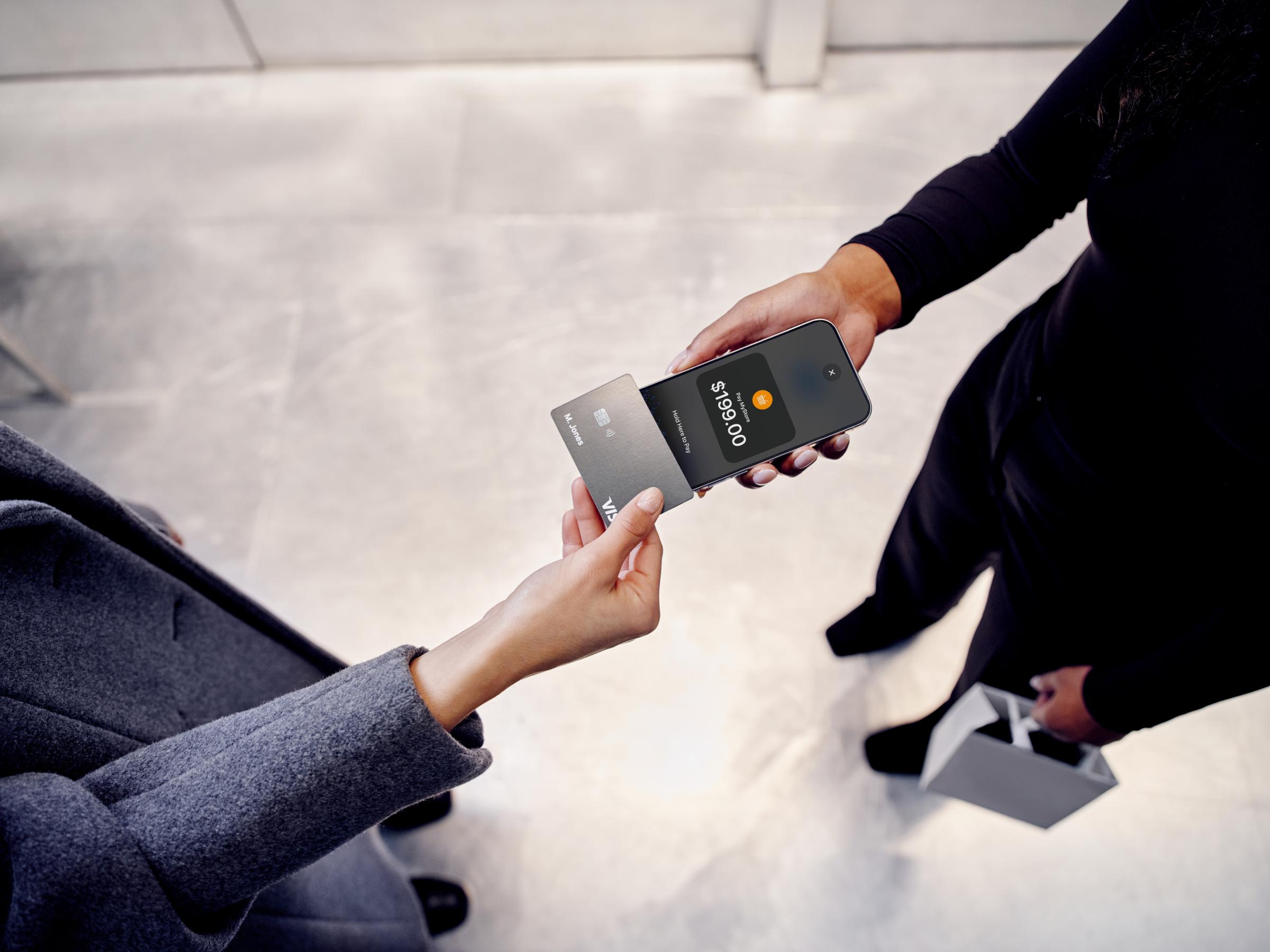 Two people exchanging a contactless payment using an Adyen card and a mobile device.