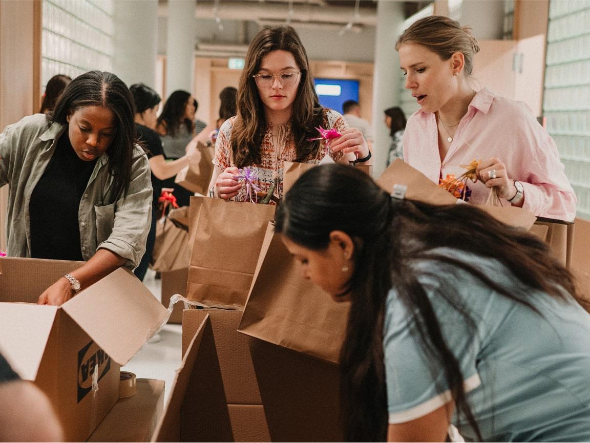 Group of people packing items into cardboard boxes in a workshop setting.