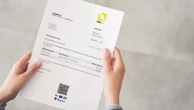 Nahaufnahme von Händen, die eine gedruckte Rechnung mit Adyen QR-Code-Zahlungsoption halten