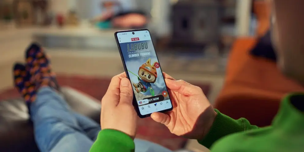 Person sitting with crossed legs holding a smartphone displaying an Adyen checkout screen.