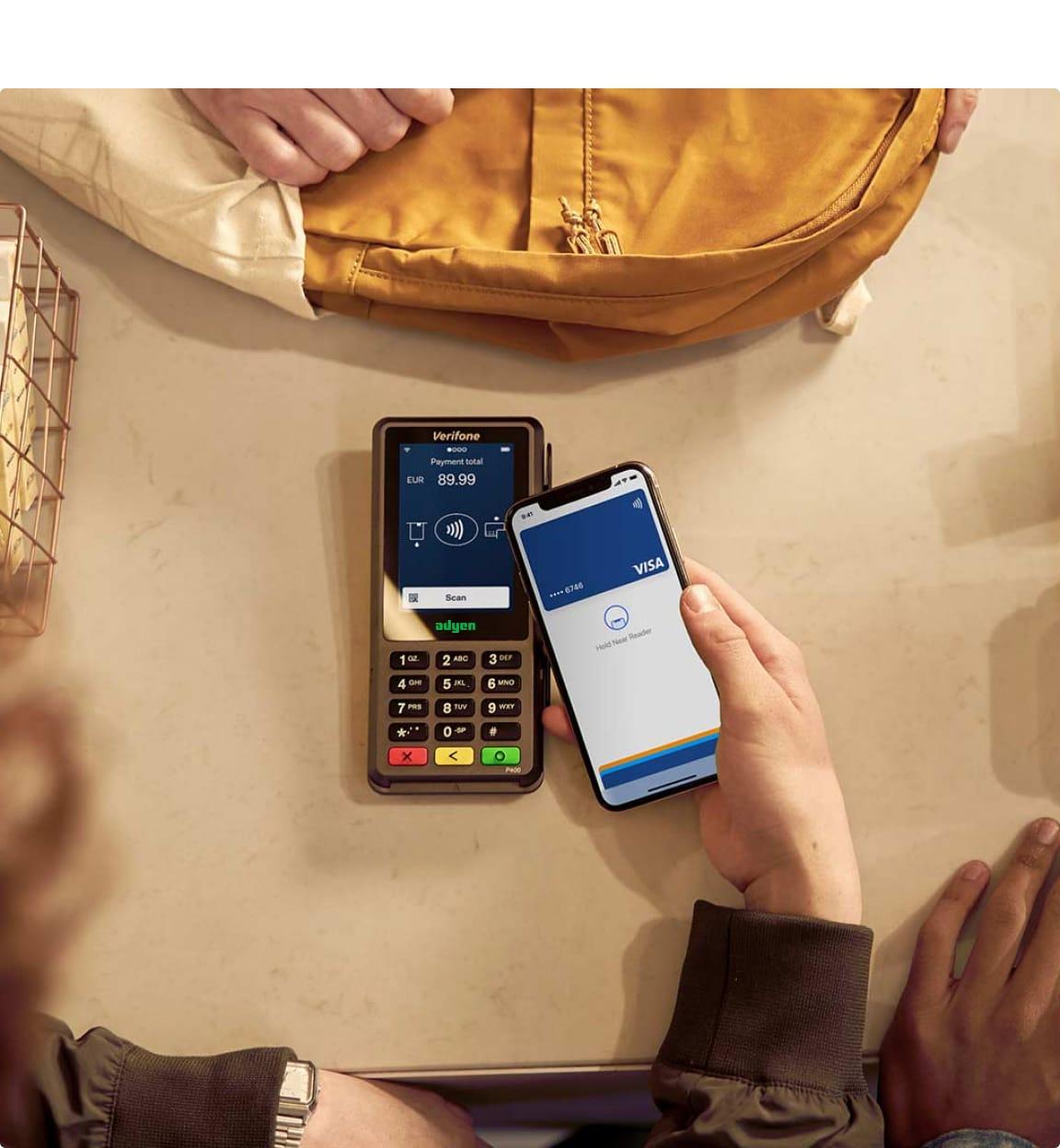 Person using a smartphone to make a contactless payment on an Adyen terminal displaying €89.99.