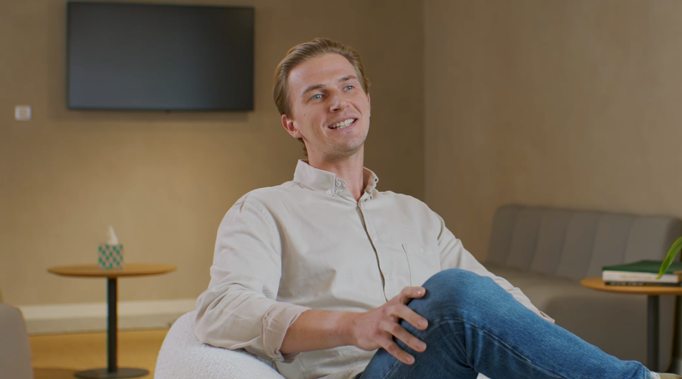 Adyen employee in a professional setting, seated with crossed legs in a modern office