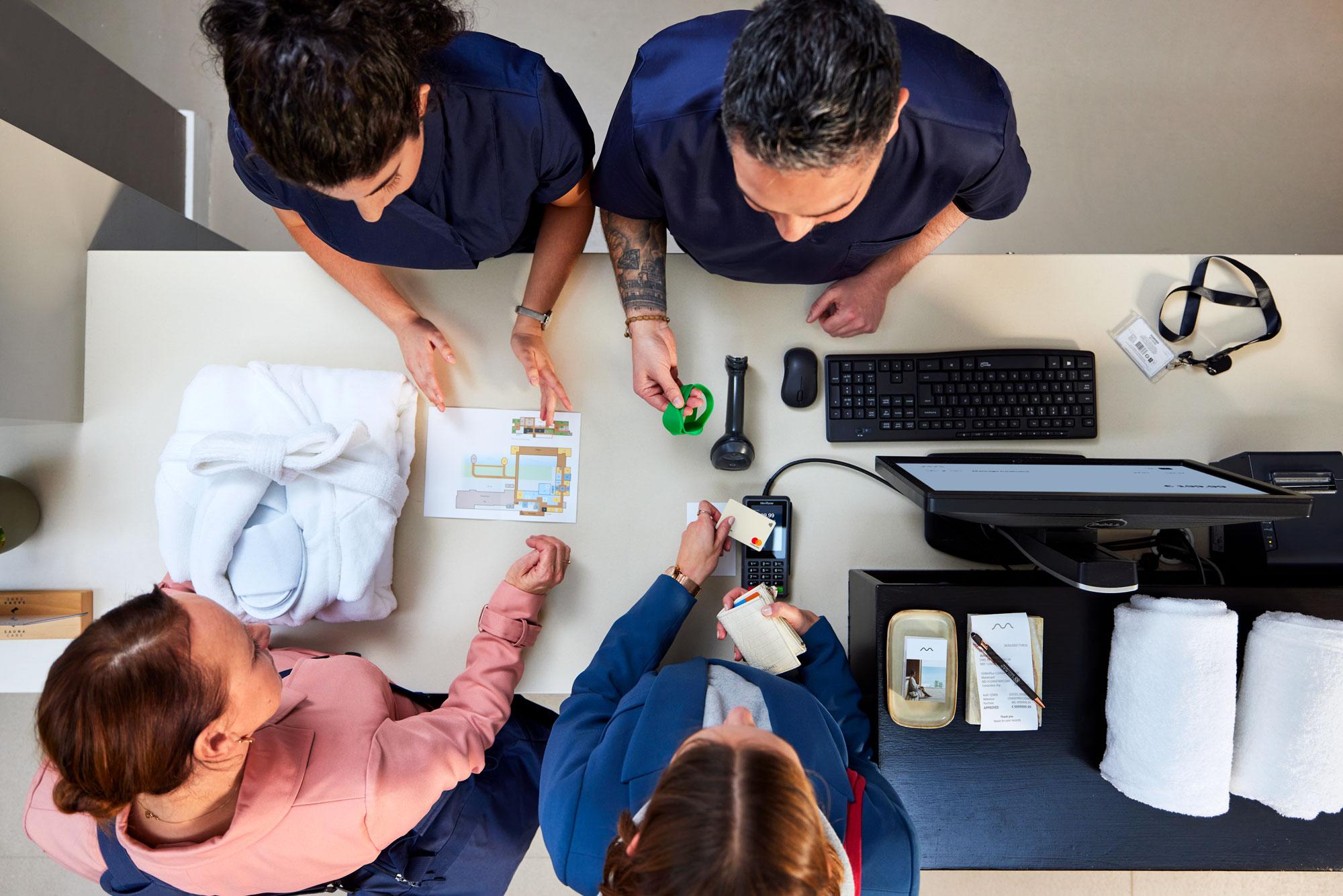 Two women paying for spa and wellness by tapping a card on Adyen's P400 terminal.
