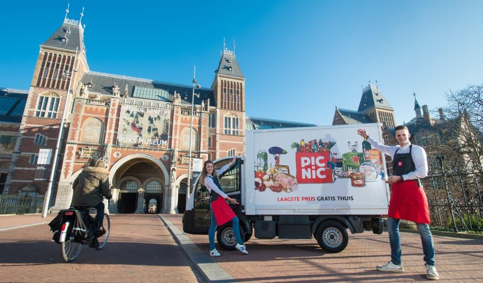 Delivery person with a Picnic electric van in front of the Rijksmuseum on a sunny day.