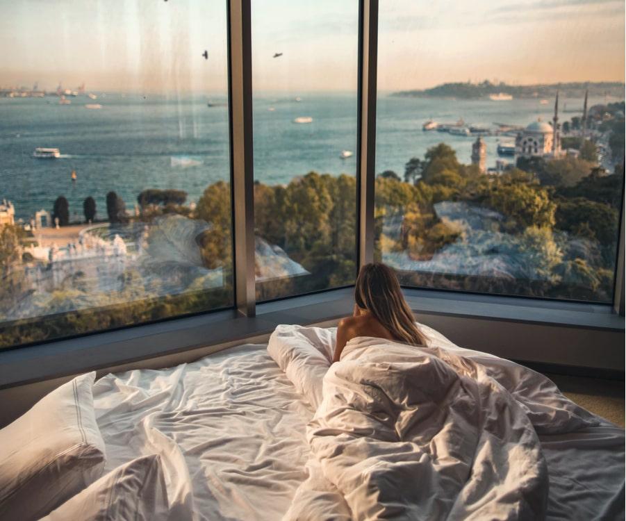 Femme allongée dans un lit d'hôtel avec vue sur l'océan