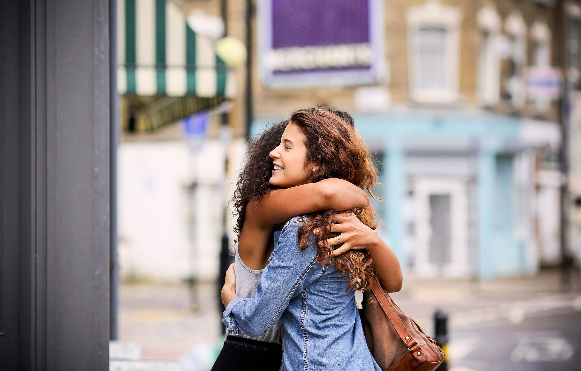 Zwei Frauen umarmen sich auf einer Stadtstraße