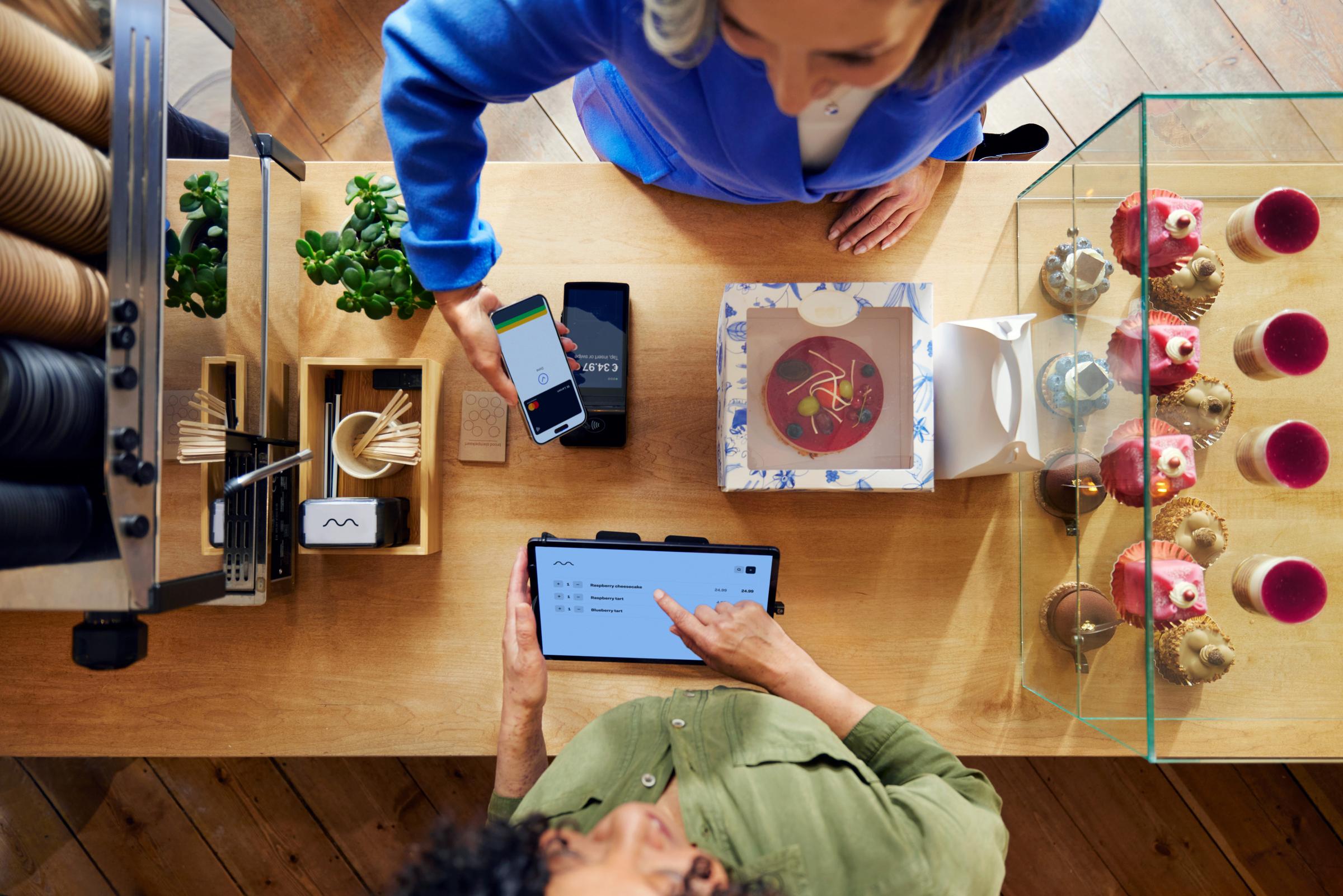 A customer in a coffee shop paying by phone using Adyen's S1F2 terminal through a SaaS platform for food & beverage