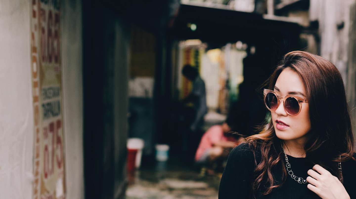 Mujer elegante con gafas de sol caminando en un callejón de la ciudad.