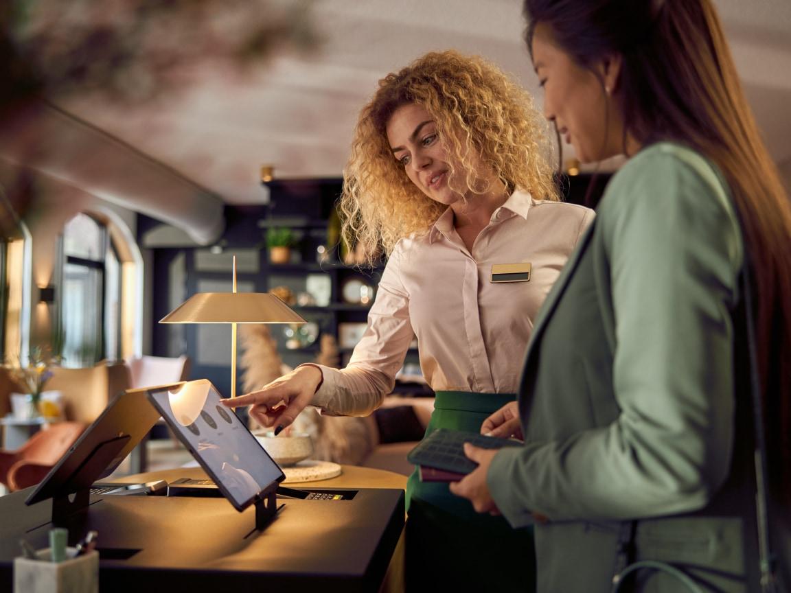 Una sonriente camarera asistiendo a un cliente con un pago en un terminal de Adyen.