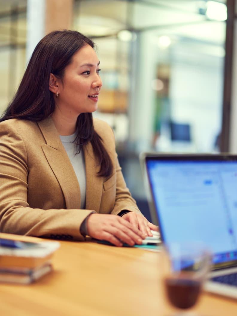 Femme professionnelle travaillant sur un ordinateur portable dans un cadre de bureau moderne.