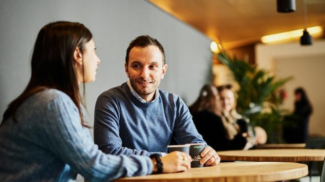 Duas pessoas tendo uma conversa em um café com um cartão de pagamento na mesa