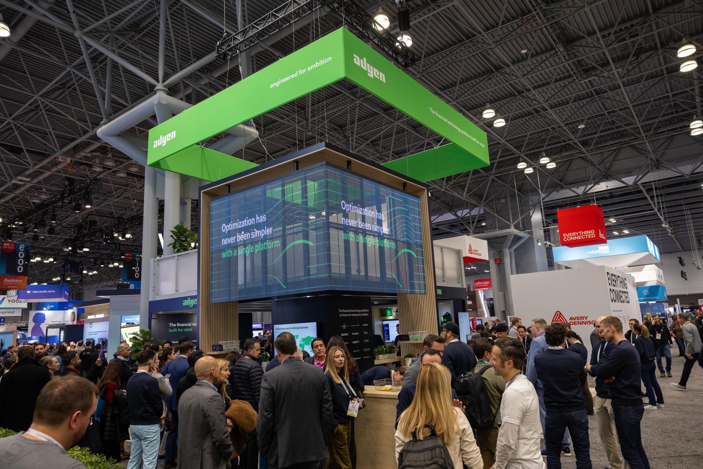 Participantes interagindo no stand da Adyen durante um evento NRF