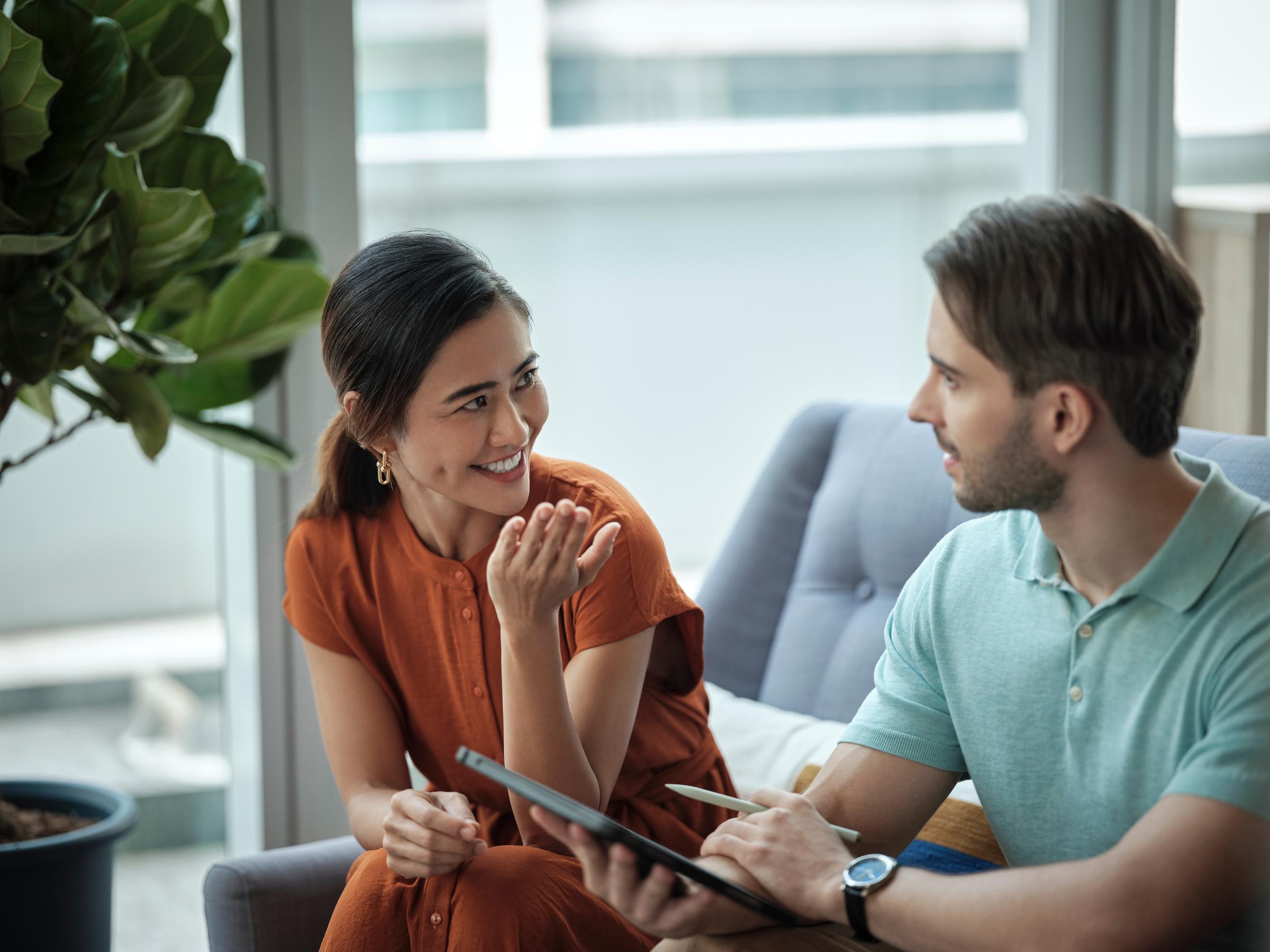 A close up view of a woman and man sitting on a sofa discussing 