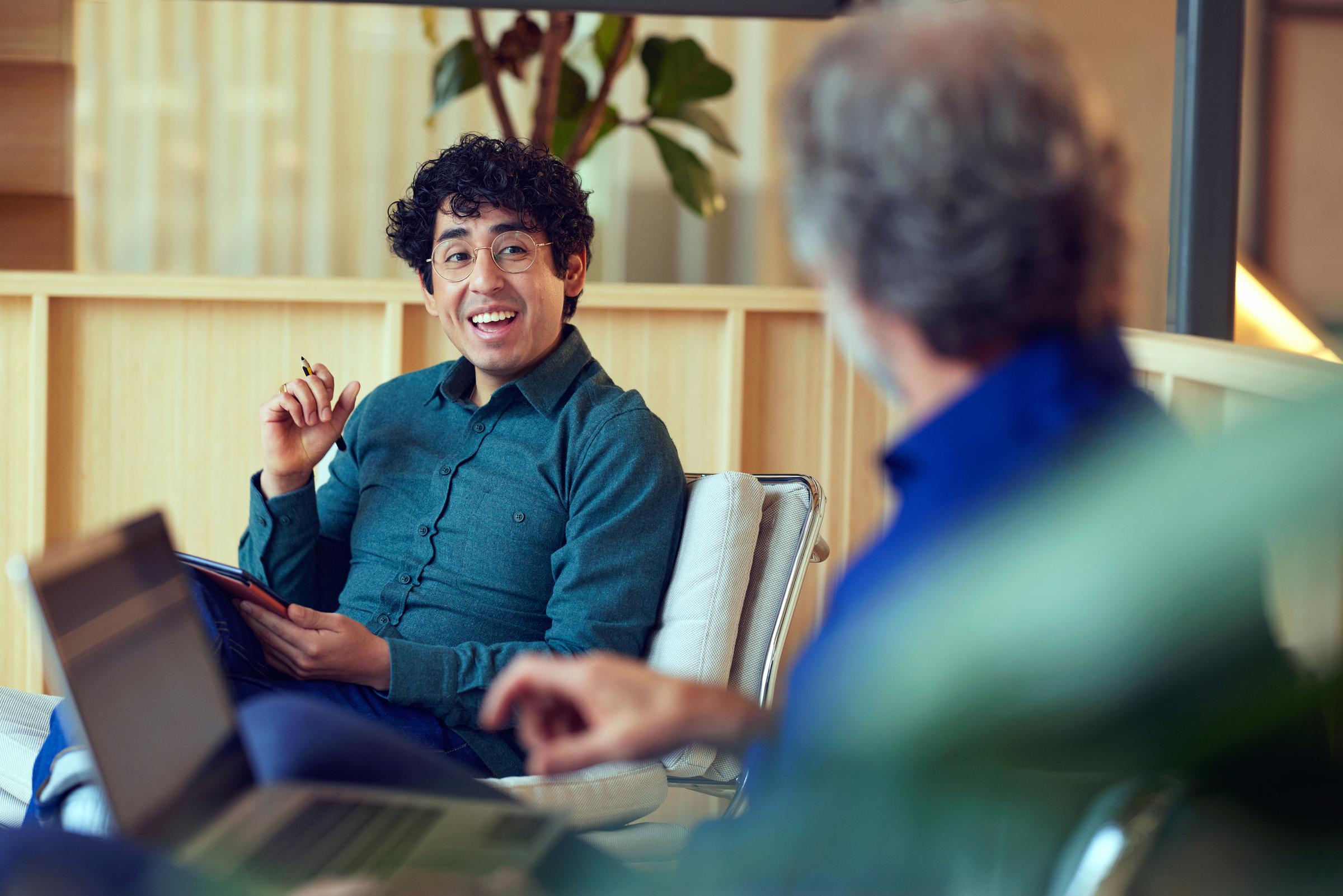 Colegas sorridentes no escritório da Adyen discutindo à mesa.