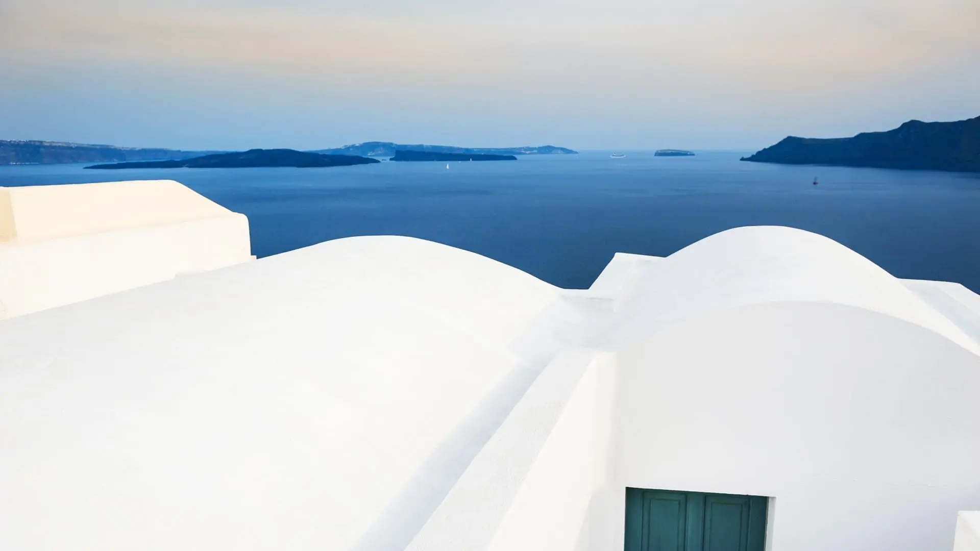 White domed rooftop overlooking the calm blue sea during dusk in Greece.