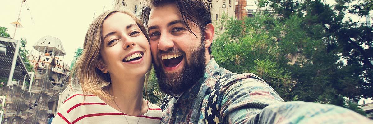 Two people taking a selfie with a cathedral under renovation in the background.