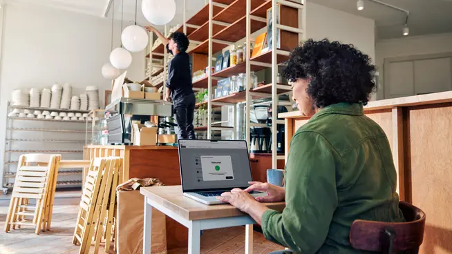 Personne au comptoir d'un café travaillant sur un ordinateur portable affichant la page de paiement d'Adyen.