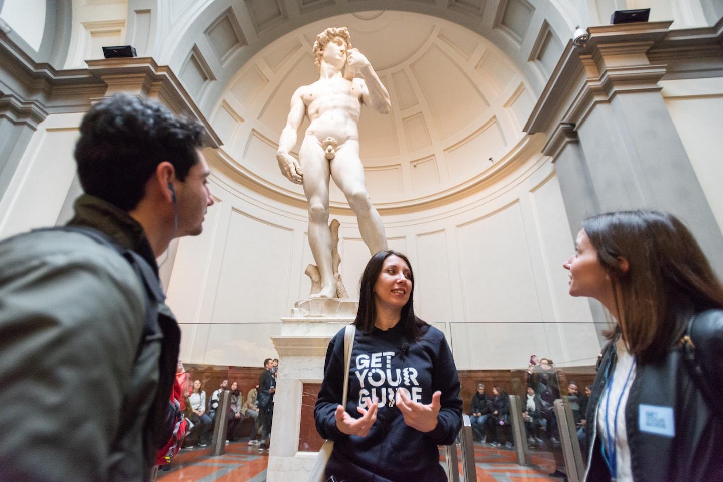 Touristen bewundern die Statue von David in einem Museumssetting