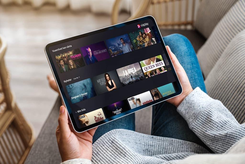 Person som holder en nettbrett som viser et strømmetjeneste-grensesnitt med filmvalg
