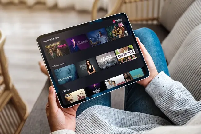 Person holder en tablet med en streamingtjenestes brugerflade med filmvalg