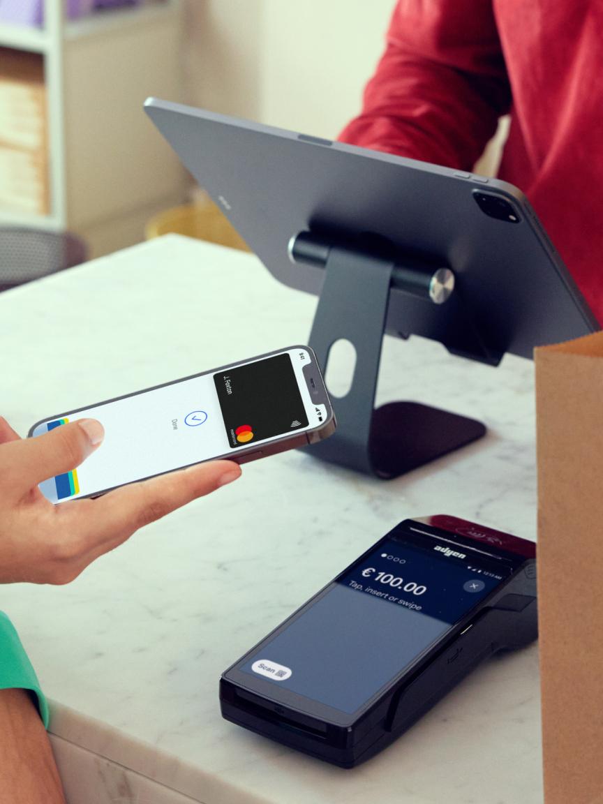 Personne utilisant un smartphone pour effectuer un paiement sur un terminal Adyen.