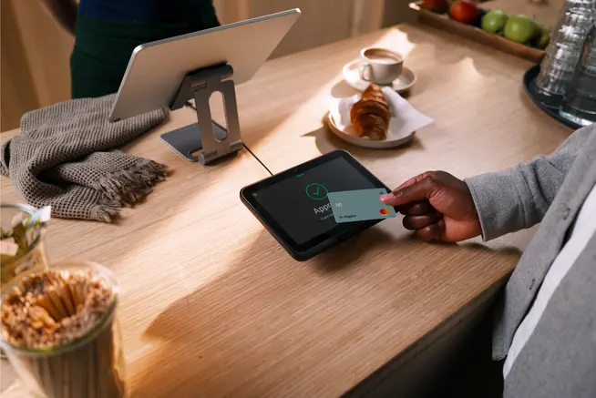 Pago con tarjeta Mastercard en terminal SFO1 en un entorno de cafetería panadería