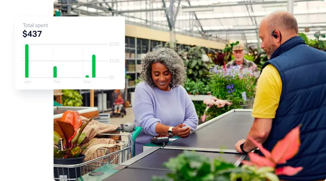 Person checking out at a garden centre using an Adyen payment terminal displaying a chart of total spent
