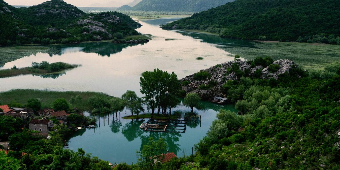 Vista aérea de un río sereno que fluye a través de un paisaje exuberante con casas y barcos.
