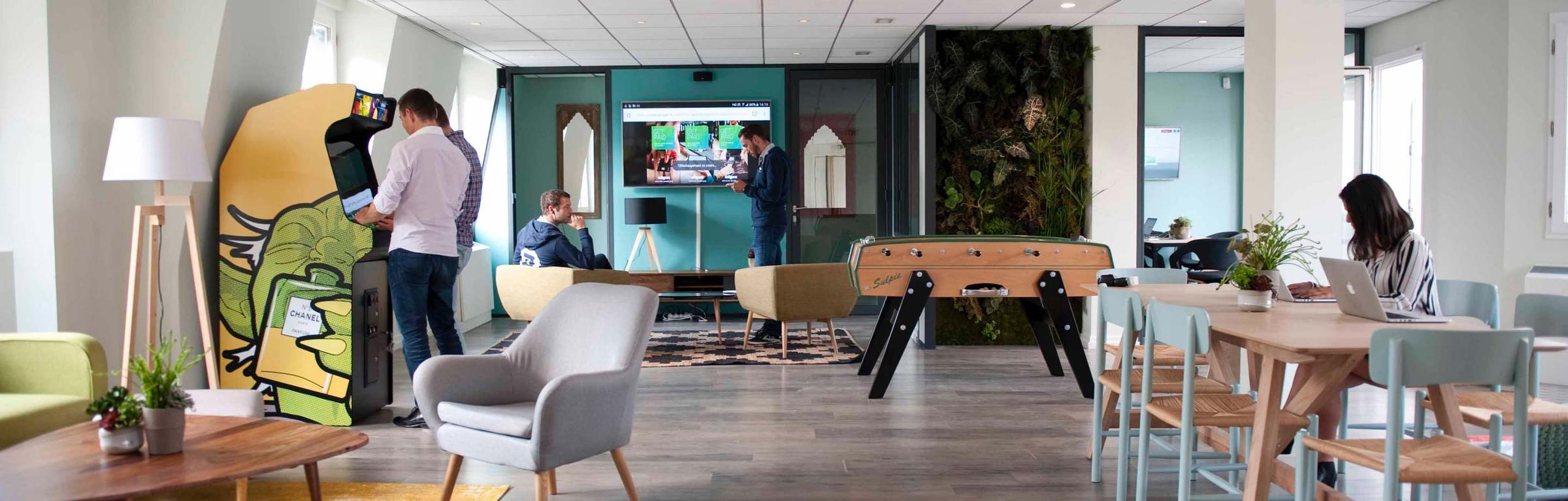 Espace de détente moderne de bureau avec des employés travaillant, se relaxant et jouant au baby-foot.