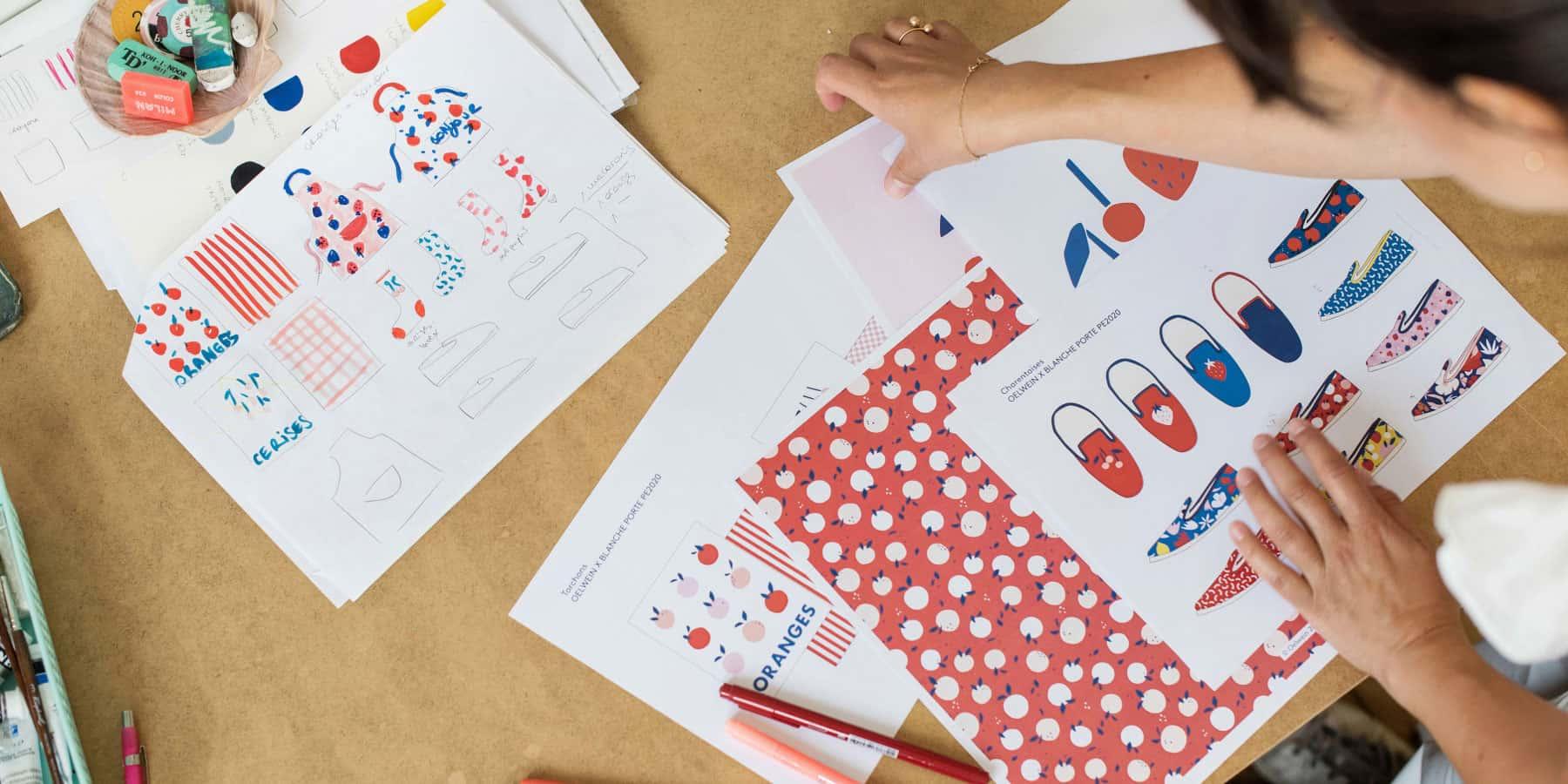 Personne examinant des impressions de conception colorées pour divers produits sur une table.