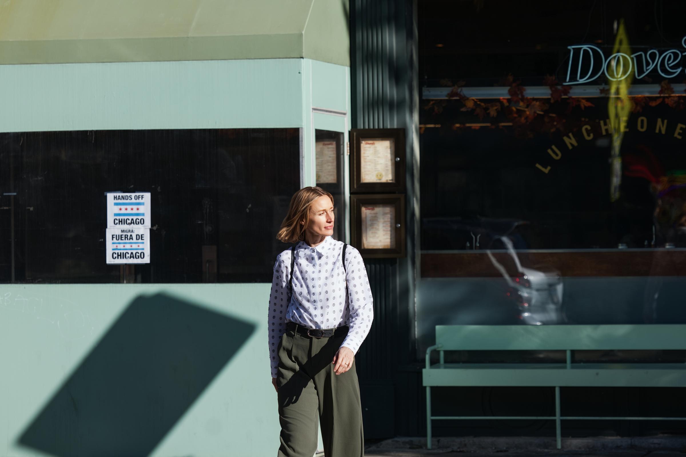 A person standing outside a building near a window with signage, possibly waiting or passing by