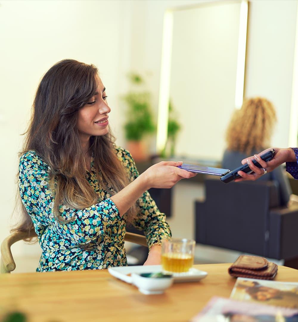 Uma mulher pagando via POS móvel da Adyen em um café